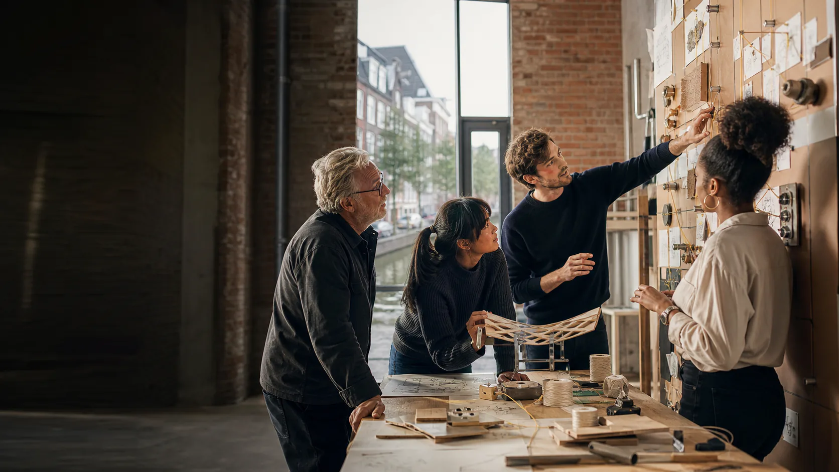 Illustrative scene of four builders debating a physical process wall in an Amsterdam workspace