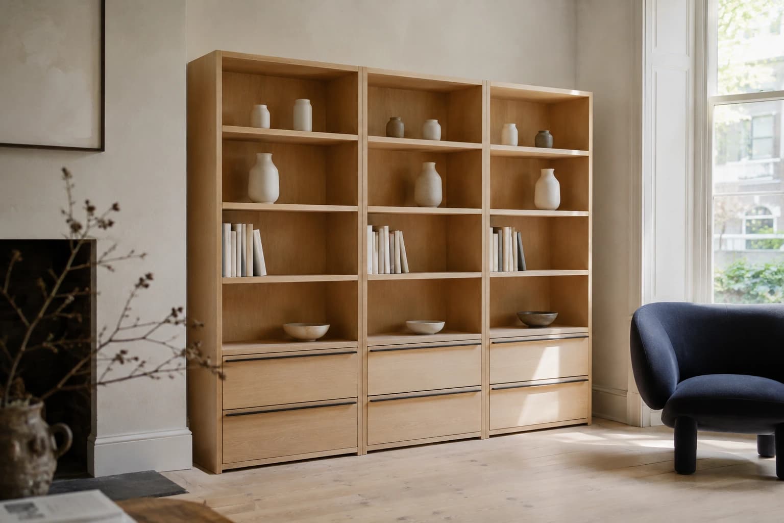 Illustrative VAK oak storage system with open shelves and drawers in a bright interior beside a navy-blue chair